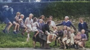 The photo is from the collection of Jill Mapstone and shows children on the village green, Bernards' Place, which was gifted by Lady Pinney (the older woman in the photo) and is named in memory of her brother and son, who were both called Bernard.